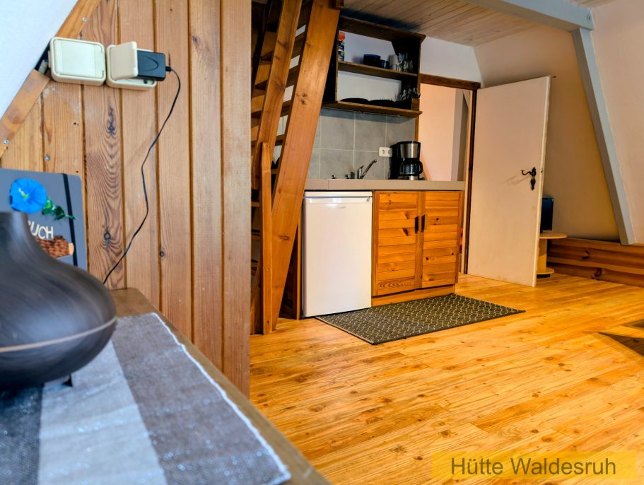 Wohnbereich mit Treppe Aufgang zum Obergeschoss und Durchgang zur Küche in der Finnhütte